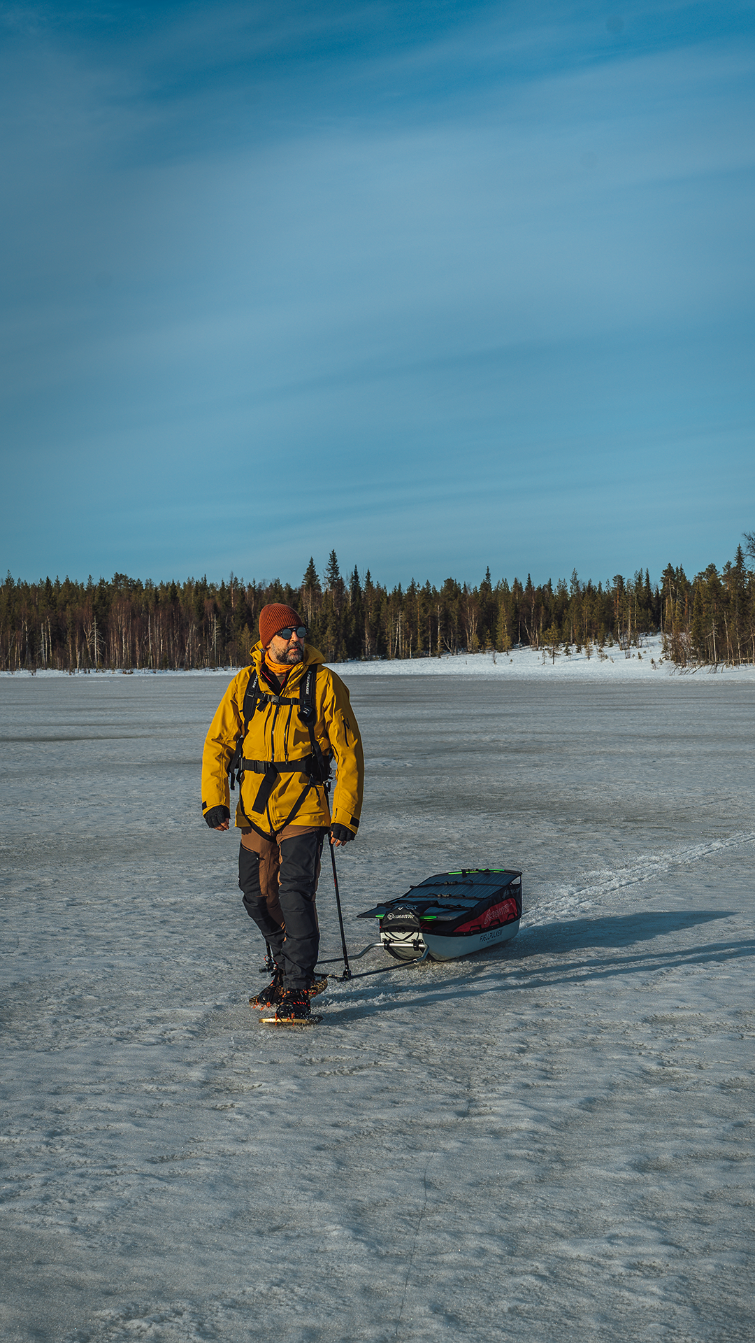 Engin Senli walking across a frozen lake with outdoor equipment